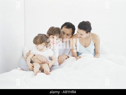 Famiglia seduta a letto insieme Foto Stock
