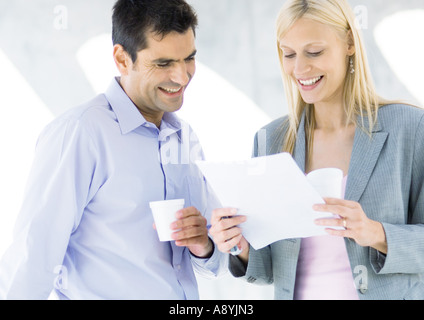 I soci dell'azienda avente il caffè e la lettura del documento e di ridere Foto Stock