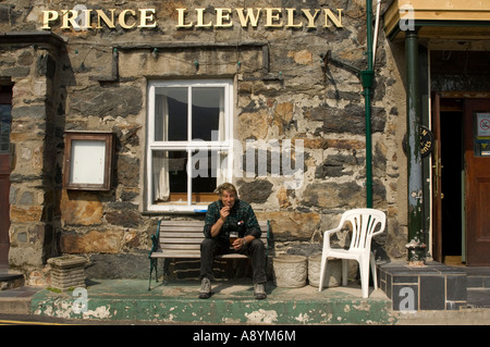 Uomo di bere birra in sole seduto fuori il principe Llewelyn pub Beddgelert snowdonia national park Gwynedd Galles del nord Foto Stock