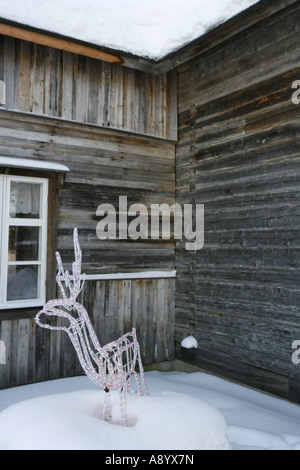 Statua di renne decorate con luci di Natale nella parte anteriore del log cabin in Lapponia la natura artica. Foto Stock