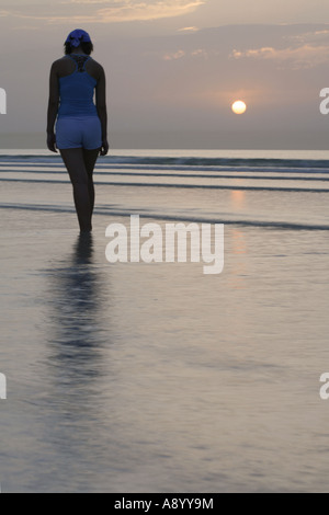 Femmina Lone camminando lungo la spiaggia. Foto Stock