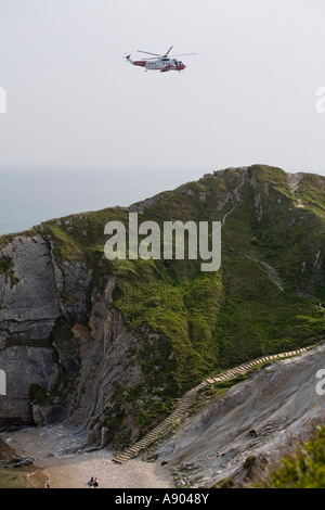 Sea King elicottero vola in testa come ai visitatori di rilassarsi sulla spiaggia di uomo o la guerra Bay nei pressi di porta di Durdle Dorset Regno Unito Foto Stock