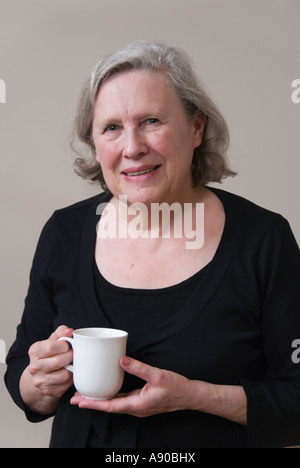 Una signora anziana di bere una tazza di caffè o di tè Foto Stock