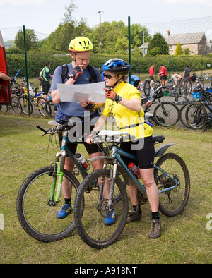 Due persone che studiano la mappa per la bicicletta in fase di gara avventura Wales UK Foto Stock