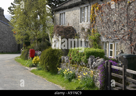 Un cottage in villaggio Conistone nel Yorkshire Dales National Park in un assolato pomeriggio di estate. Fiori e secco del muro di pietra di fronte sulla strada.