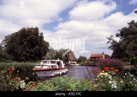 Inglese Norfolk Broads barca a Hunsett Mill mulino a vento e cottage casa con fiori estivi lungo il fiume a Stalham River ANT East Anglia Inghilterra Regno Unito Foto Stock