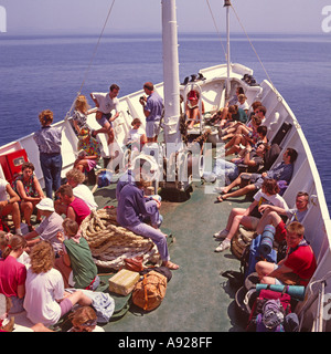 Giovani backpackers seduti sul ponte di prua di un inter-island ferry in barca a vela tra le isole greche - Grecia Foto Stock
