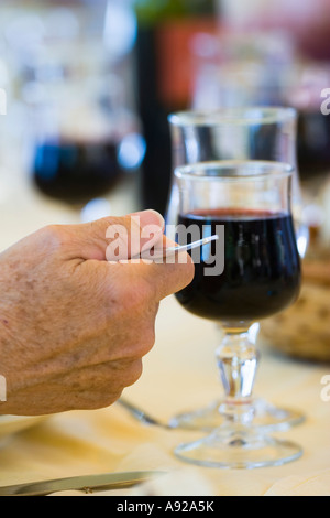 S Man mano che tiene la forcella di vino rosso in vetro del vino biancheria panno tavolo pranzo Foto Stock