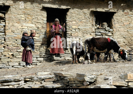 Ragazza donna e bambino in stoffa tradizionale ad una pietra costruito casa Nar-Phu Chyakhu Regione Annapurna Nepal Foto Stock