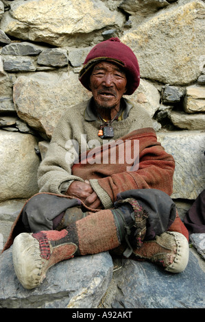 Il vecchio uomo che indossa cappello di lana e stivali in pelle di yak in corrispondenza di un muro di pietre Phu Nar-Phu Regione Annapurna Nepal Foto Stock