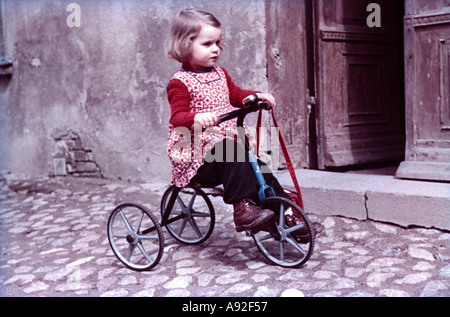 Foto storiche bambino con un triciclo a giocare in strada 1960 Foto Stock