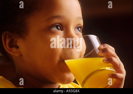 Bambino 4 anno vecchia ragazza di bere un bicchiere di succo di arancia in casa sua cucina Foto Stock