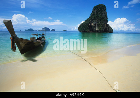 Barca sulla spiaggia, lone rock formazione in background Foto Stock