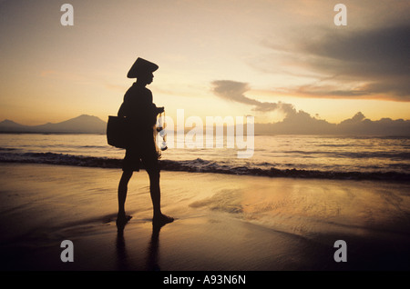 Asian pescatore sulla riva a guardare il tramonto Foto Stock