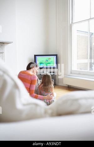 Madre e figlia (5-6) guardando cartoni animati in televisione, vista posteriore Foto Stock