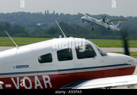 Flybe aereo decolla da l'aeroporto di Southampton con aeromobili leggeri in attesa sulla pista. Foto Stock