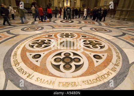 Chiudere orizzontale del marmo antico pavimento intarsiato all'interno del Duomo con i turisti in piedi guardando l'iscrizione. Foto Stock