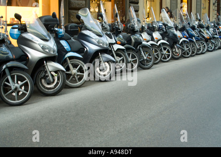 Chiudere orizzontale di una fila di molti ciclomotori e scooter parcheggiato sul ciglio della strada a Firenze. Foto Stock