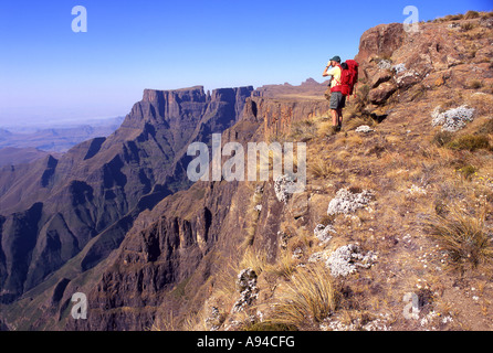 Un escursionista si affaccia dal vertice dell'anfiteatro sopra le colline di Drakensberg sotto Drakensberg Sud Africa Foto Stock