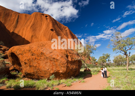 Walkers sul basamento a piedi intorno al perimetro di Ayers Rock in territori del Nord Australia Foto Stock