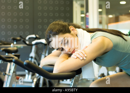 Donna in appoggio sulla cyclette Foto Stock