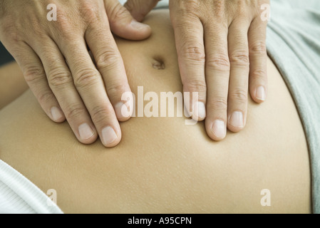 Mani dell'uomo sulla donna incinta lo stomaco, close-up Foto Stock