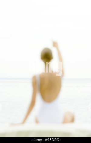 Figura femminile che indossa costume da bagno, offuscata silhouette, rivolto verso il mare in background, vista posteriore Foto Stock