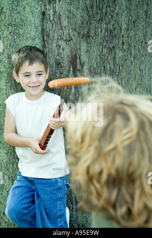 Ragazzo holding hot dog sulla estremità della forcella grande, mostra amico Foto Stock