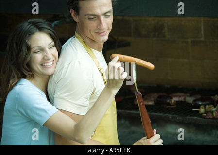 Giovane avente cookout, donna prendendo hotdog da uomo di forcella Foto Stock