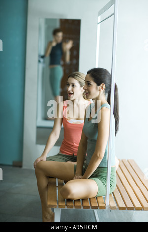 La donna guarda amico pesare se stessa in spogliatoio Foto Stock