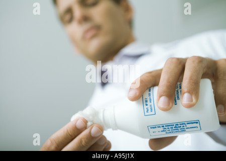 Medico versando antisettico sulla sfera di cotone Foto Stock