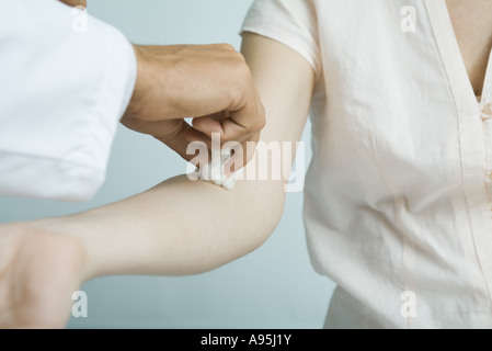 Pulizia medico della donna del braccio con un batuffolo di cotone Foto Stock