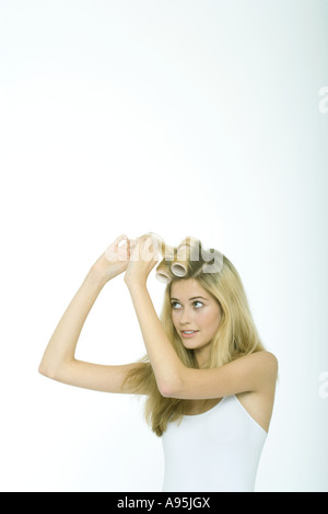 Ragazza adolescente mettendo i rulli nei capelli Foto Stock