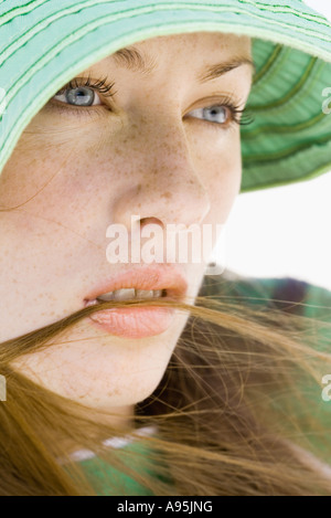 Giovane donna che indossa cappello per il sole, close-up Foto Stock