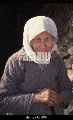 Ritratto di un vecchio contadino albanese donna musulmana che indossa un velo bianco e grigio smock lana tenendo un bastone da passeggio Foto Stock