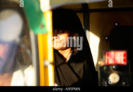 Donna indiana musulmana che indossa chador in risciò automatico al tramonto, Ahmedabad, Gujarat, India Foto Stock