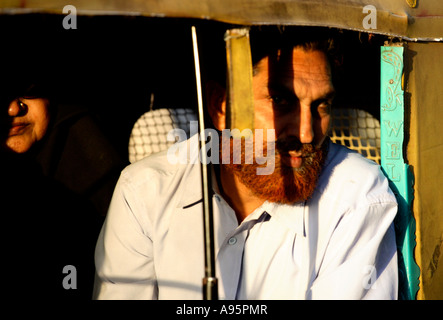 Rosso alesato musulmano indiano maschio peering da auto riskshaw, Ahmedabad, Gujarat, India Foto Stock