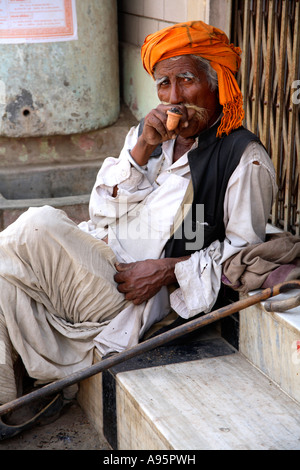 L'uomo indiano sul tubo fumatore del punto di strada, Anjar, kutch, Gujarat, India Foto Stock