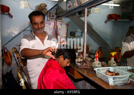 Barbiere indiano taglio capelli su ragazzo in Bhuj, Gujarat, India Foto Stock