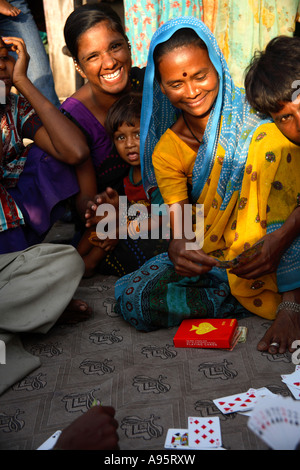 Allegra famiglia indiana che gioca carte sulla strada fuori casa slum, D'Mello Road, Mumbai, India Foto Stock