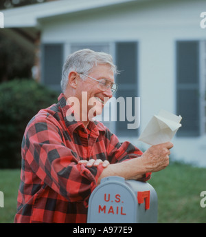 Sorridente uomo maturo in plaid shirt di lettura della scheda della casella vocale per cassetta postale Foto Stock