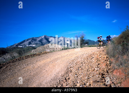 Gli amanti della mountain bike scomparirà una lunga e polverosa strada di montagna sotto i cieli blu nel sud della Spagna. Foto Stock