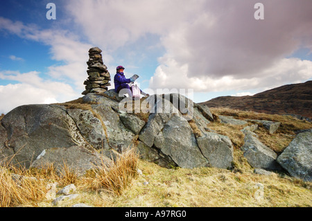 Femmina mountain biker si ferma per controllare la mappa su Birkby cadde, Eskdale. Foto Stock