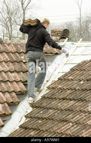 Un costruttore di montaggio di piastrelle su un tetto di una casa in estensione Foto Stock