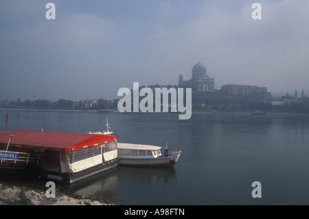 La Chiesa cattolica romana basilica a Esztergom in Ungheria attraverso il Danubio misty dalla Slovacchia con ristorante nave in primo piano. Foto Stock