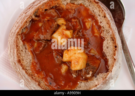 Zuppa nel pane. Una tradizionale zuppa di gulasch ceca servita in un pane intero di pane scuro a grani interi. Il pane tradizionale si chiama Sumava Foto Stock