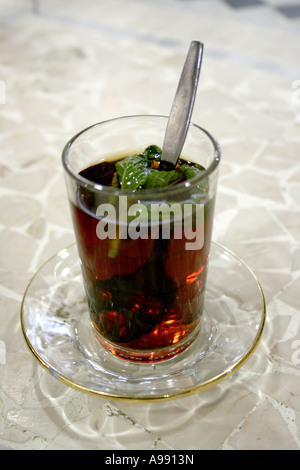 Un bicchiere di tradizionale tè alla menta libanese servito su un piattino limpido, con foglie di menta fresche e un cucchiaio, creando un'esperienza culinaria calda e autentica Foto Stock