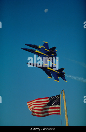 Quattro F A 18 getti dell'U Navy Blue Angels team di dimostrazione volare basso sopra un flag di U e sotto la luna in un cielo blu chiaro Foto Stock