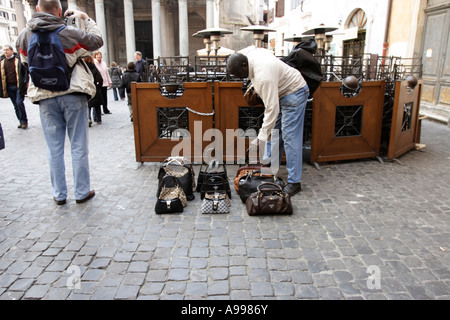 Un commerciante di strada si occupa di designer borsette in Roma, Italia Foto Stock