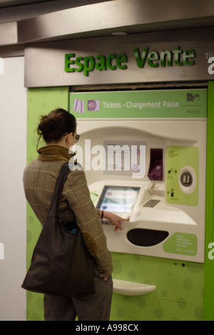 Una metropolitana passeggero femmina compra un biglietto di correre da un biglietto automatizzato della macchina su una stazione in Parigi, Francia Foto Stock